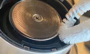 Szczoteczka czyści młynek do kawy w ekspresie DeLonghi. Drobne otwory sitka wymagają regularnego czyszczenia, by kawa była zawsze świeża.