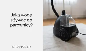 Jaka woda do parownicy? Czarna parownica Steam Master z przezroczystym zbiornikiem na wodę, stojąca na jasnym dywanie.